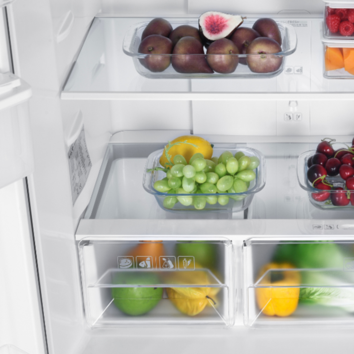 Refrigerator interior with glass shelves. It contains fruits like figs, grapes, and cherries.