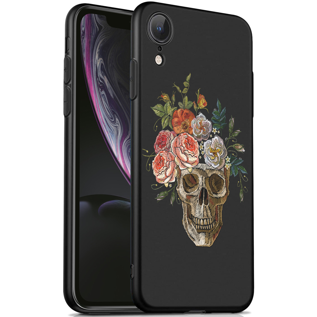 Coque de téléphone noire avec un motif de crâne et des fleurs. La coque est sur un téléphone. Le fond est flou.