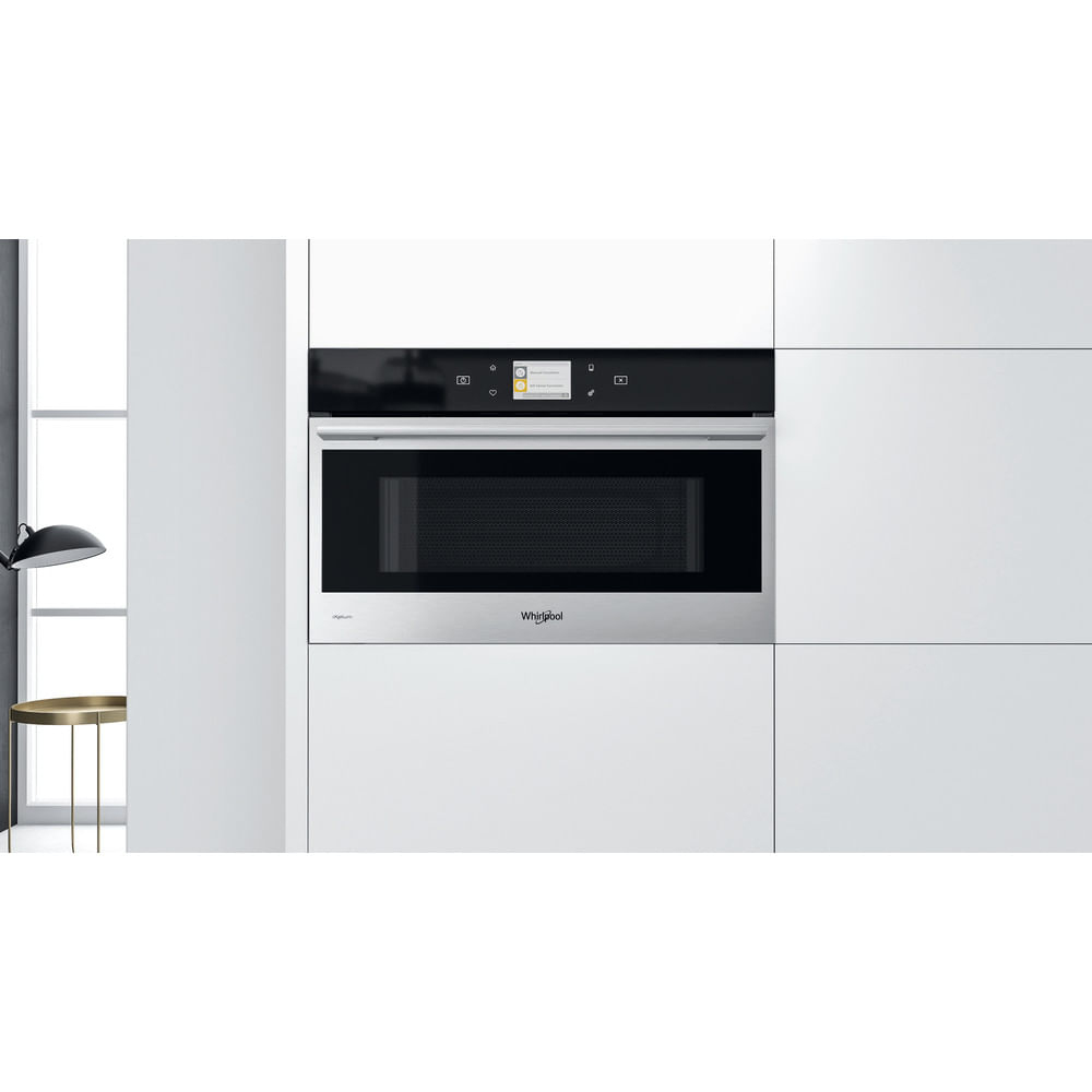 Whirlpool magnetron ingebouwd in een witte kast. Zwart frontpaneel. Schone witte keukenomgeving.