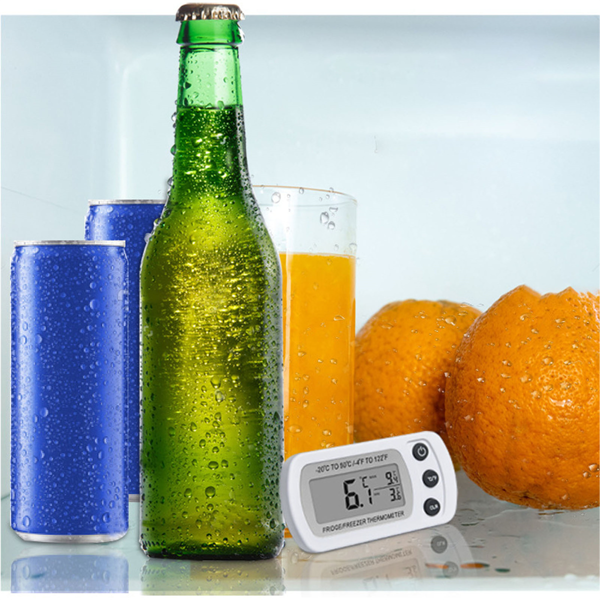 Eine grüne Bierflasche, zwei blaue Dosen, ein Glas Orangensaft und Orangen.