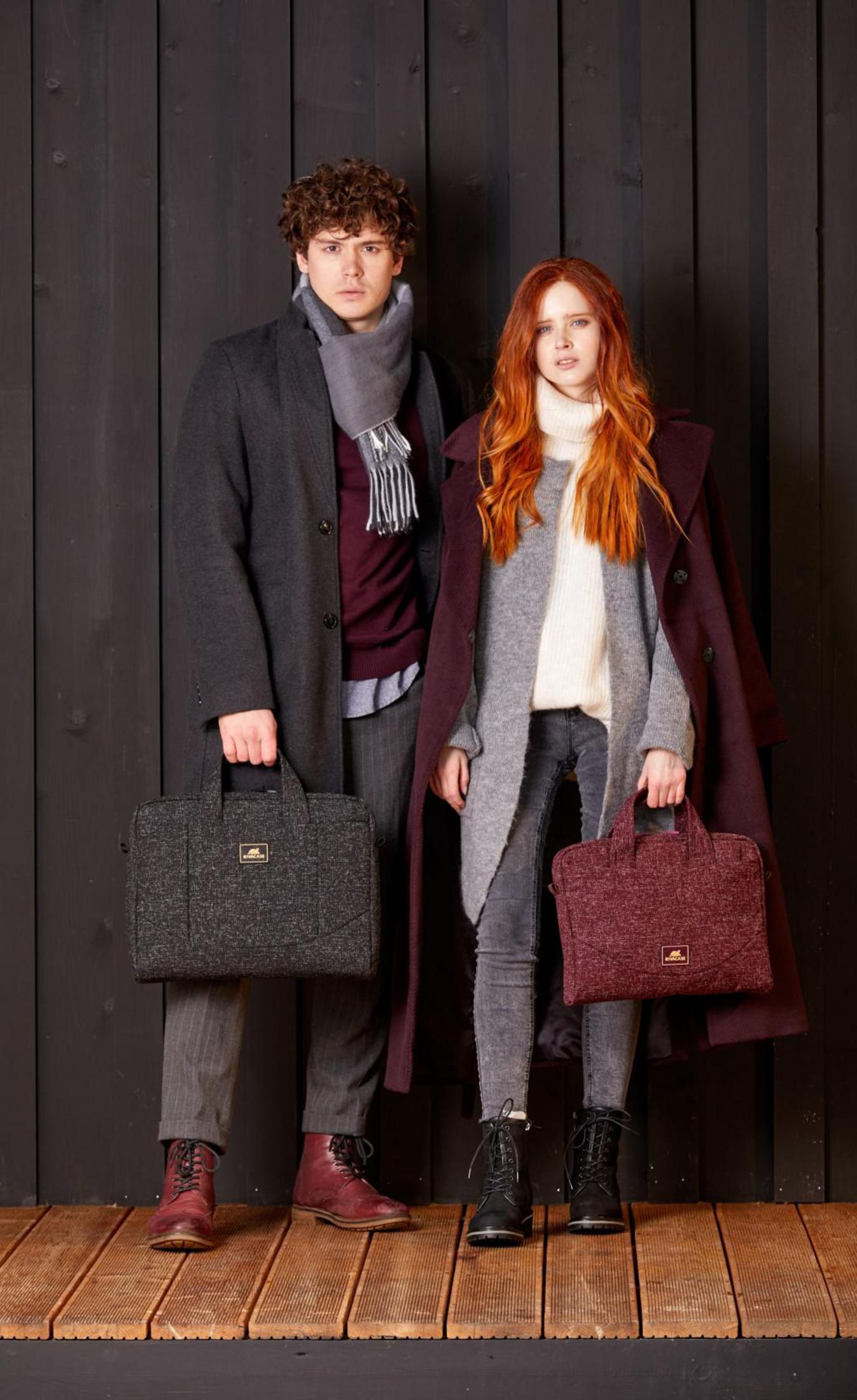 Paar, Mann im Mantel, Frau im Mantel, beide halten Taschen. Holzboden.