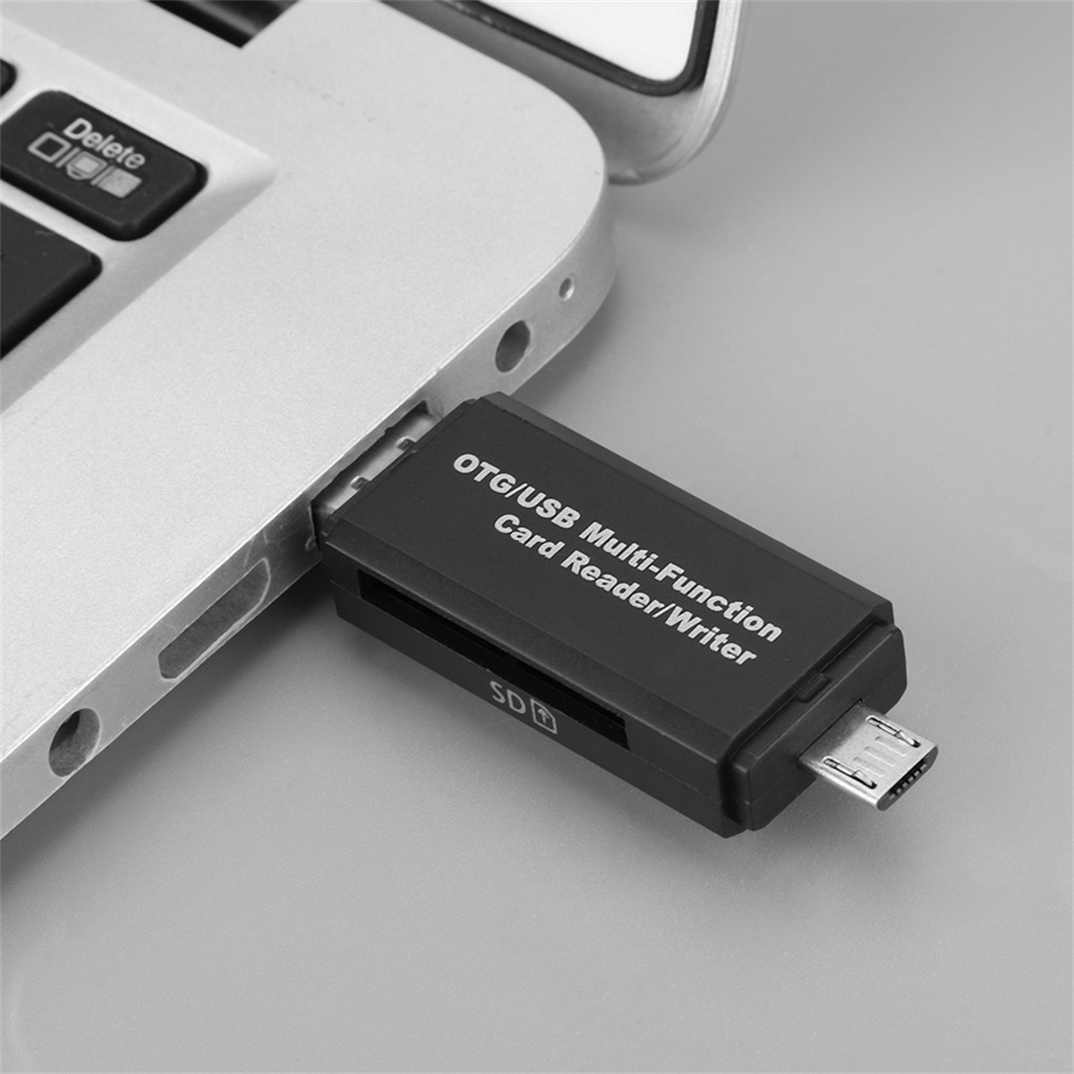 Ein schwarzer USB-OTG-Kartenleser, der in einen silbernen Laptop eingesteckt ist. Der Leser ist beschriftet.