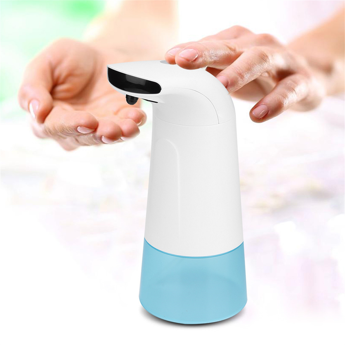 Ein automatischer Seifenspender, weißer Körper, blauer Sockel, mit Händen einer Person darüber.