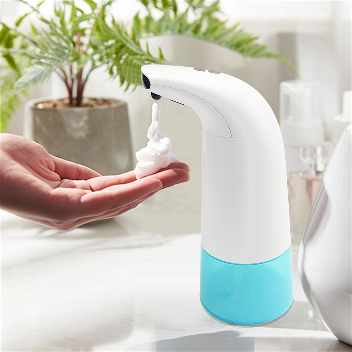 Hand empfängt Schaum von einem weißen und blauen automatischen Seifenspender.