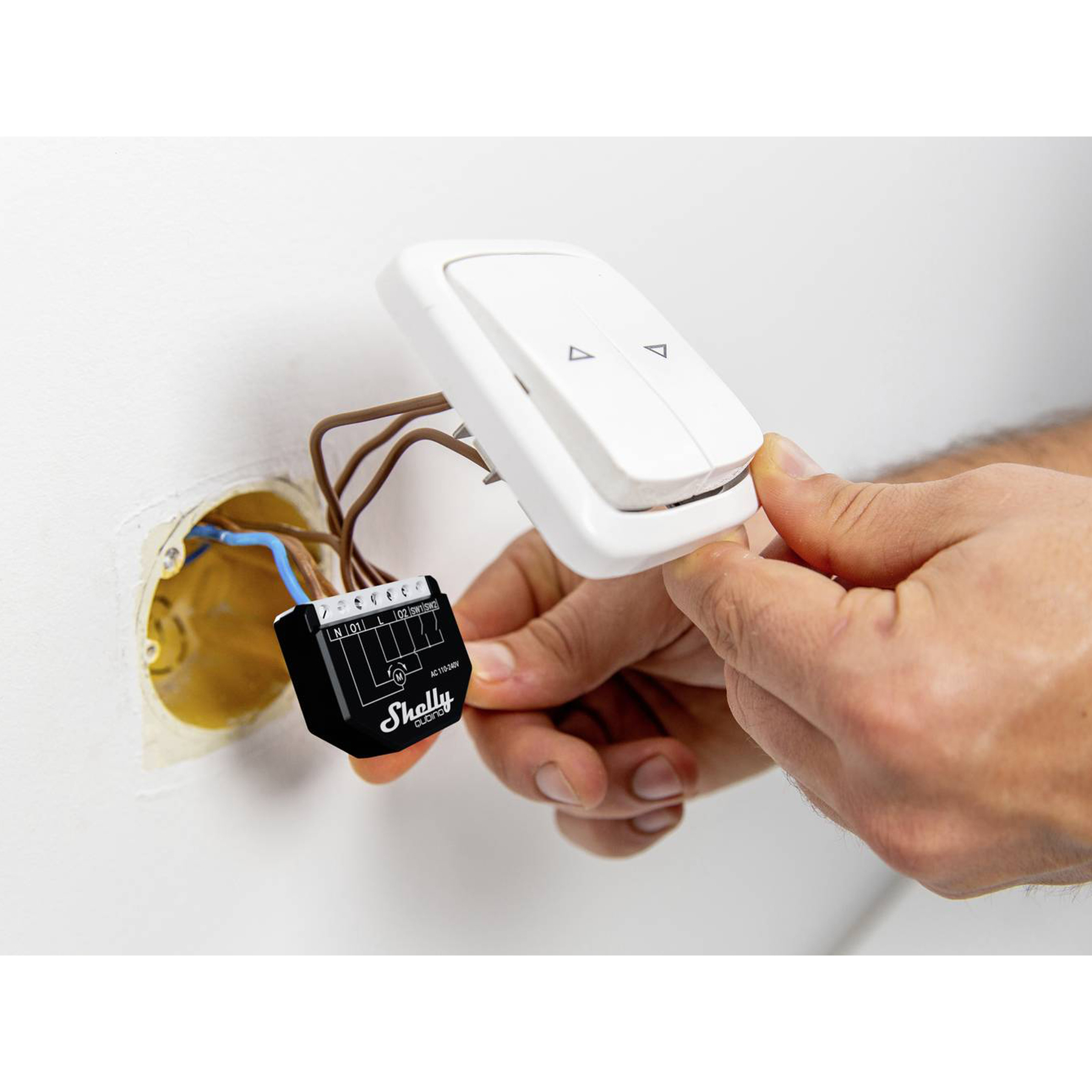 Hand installiert einen weißen Lichtschalter an einer Wand, mit Drähten und einem schwarzen Gerät.