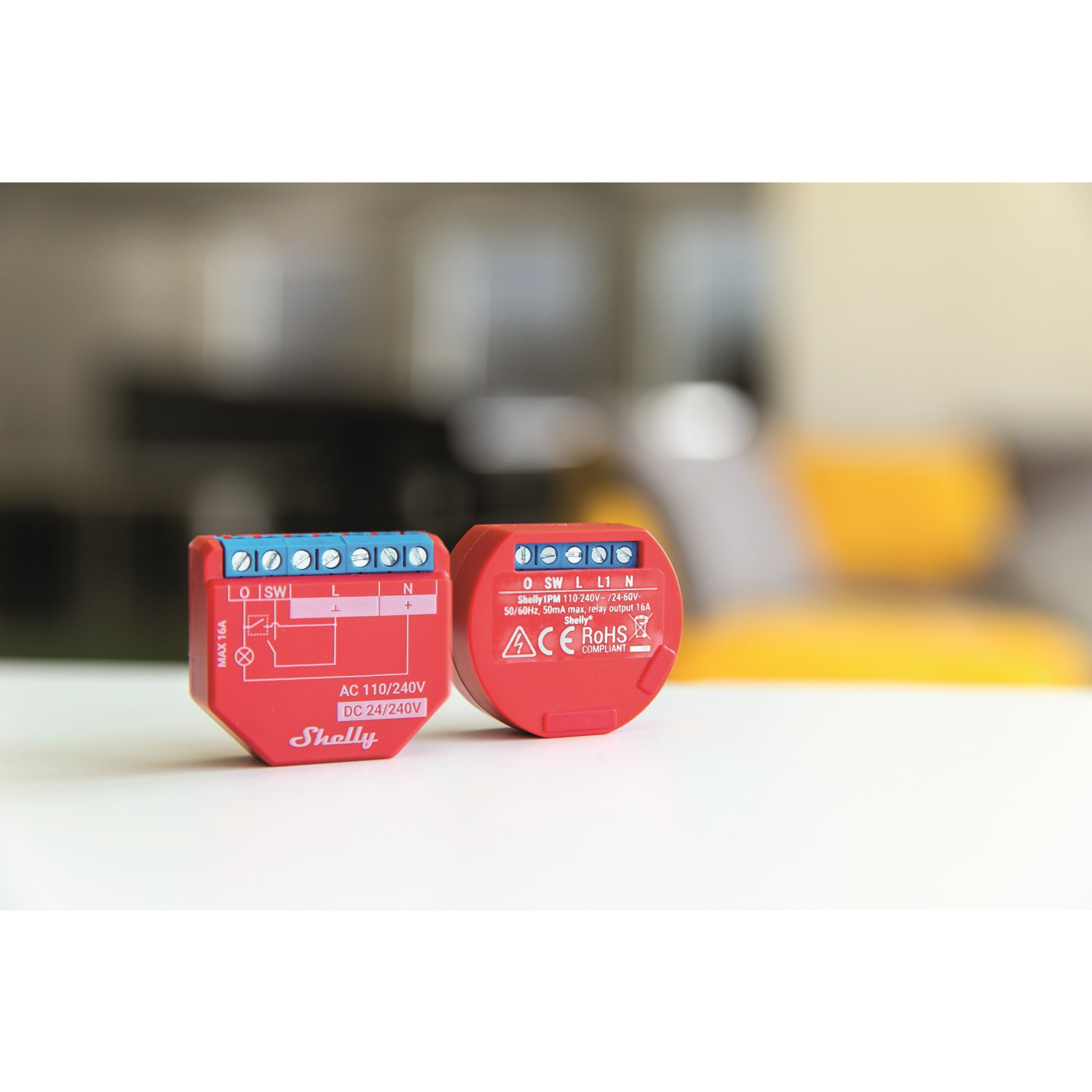 Zwei rote Smart-Home-Geräte auf einem weißen Tisch.