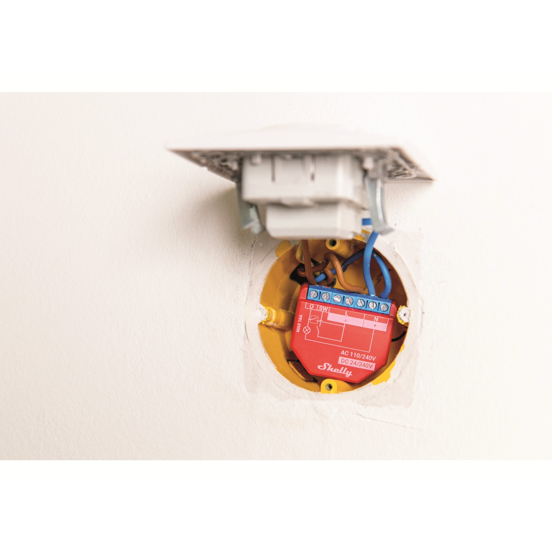Rotes Shelly Smart Home Gerät in der Wand installiert. Drähte sind angeschlossen. Die Wand ist weiß.