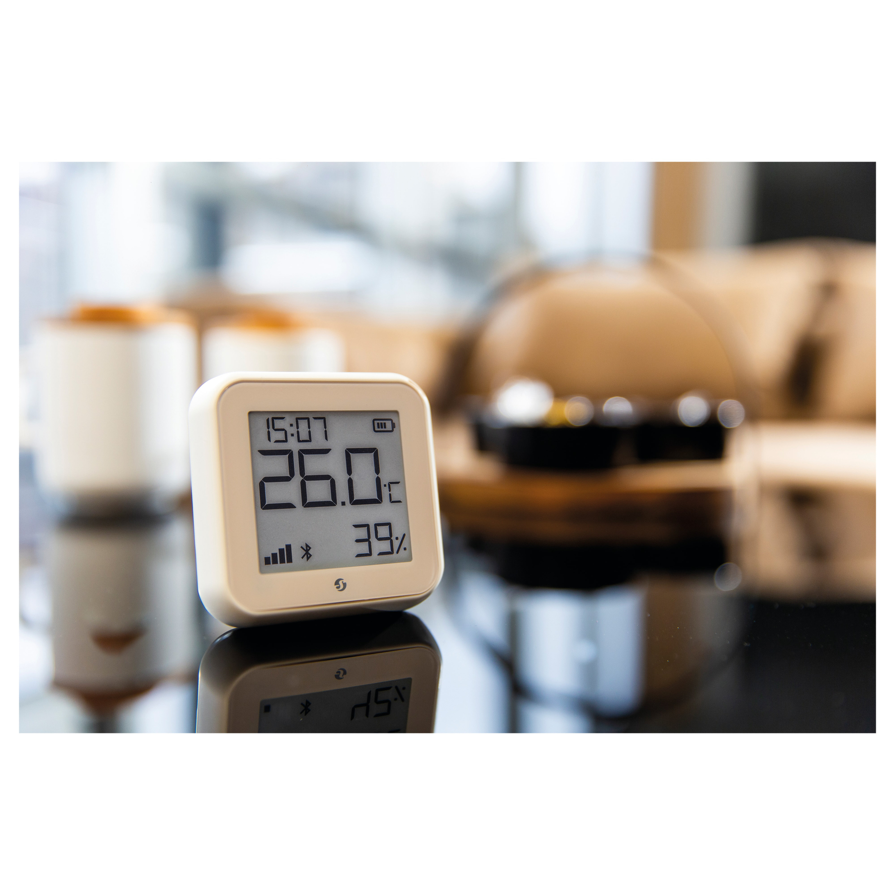 Kleine, weiße Digitaluhr, die Zeit, Temperatur und Luftfeuchtigkeit anzeigt. Schwarzer Hintergrund.