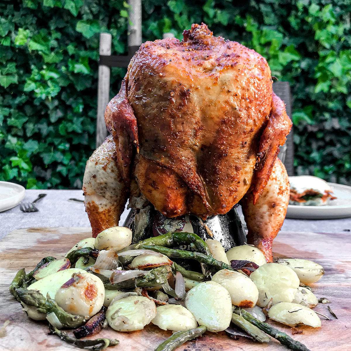 A roasted chicken with vegetables on a wooden board. Green background.