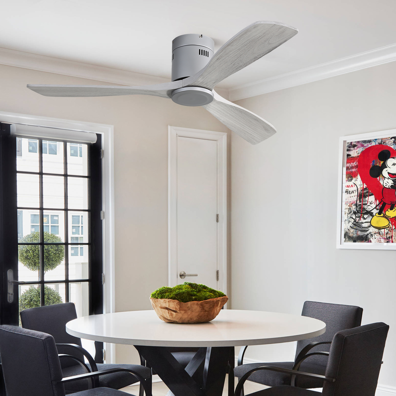 Ein Raum mit Deckenventilator, rundem Tisch und Stühlen. Ein Gemälde und eine Tür sind sichtbar.