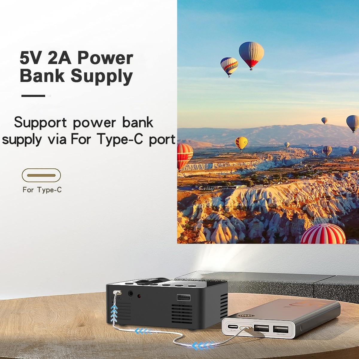 Eine Powerbank und ein Projektor mit Heißluftballons im Hintergrund.
