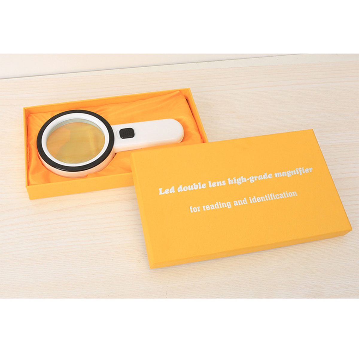 Lupe in einer orangefarbenen Box, beschriftet mit 'Led double lens high-grade magnifier for reading and identification'.