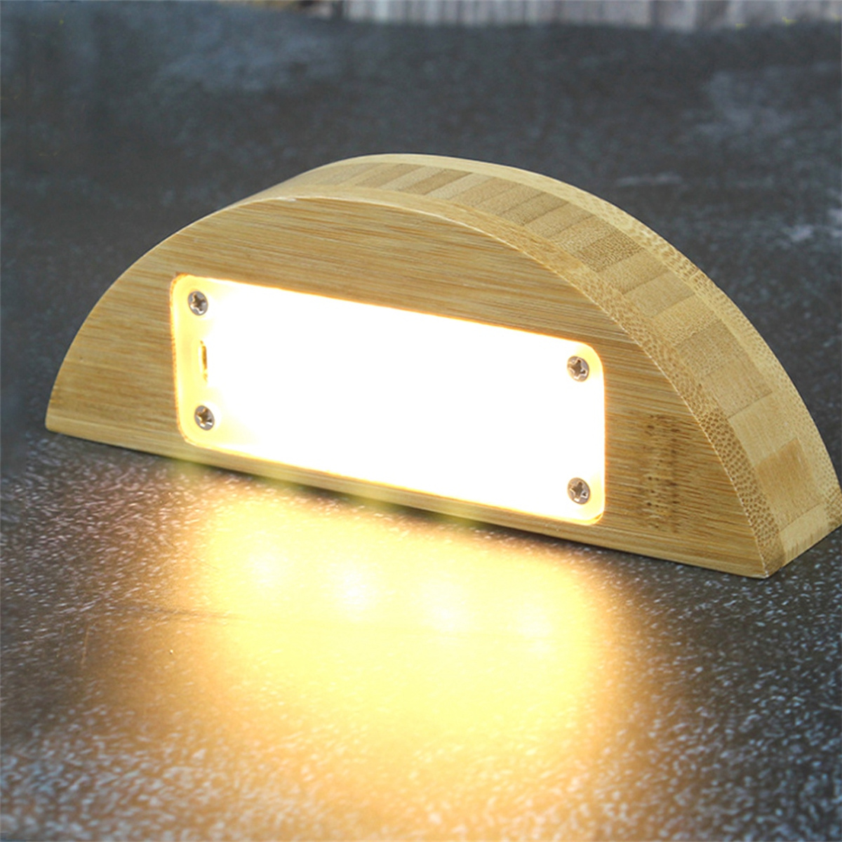 Ein Holzlicht mit hellem weißem Licht, mit halbkreisförmigem Design auf grauer Oberfläche.