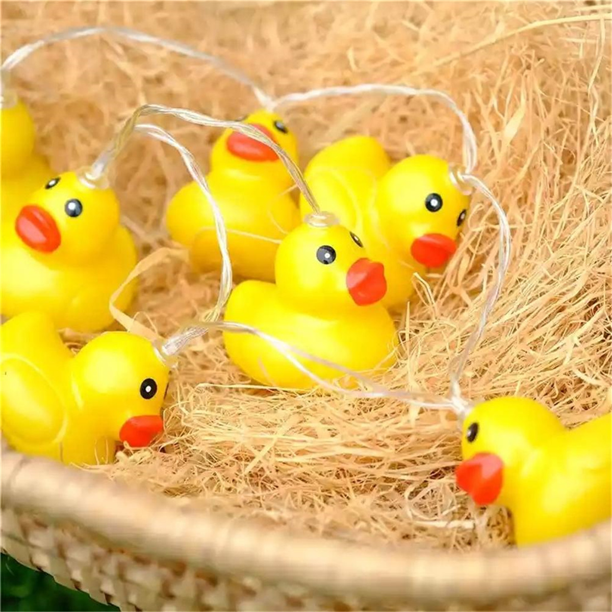 Lichterkette mit gelben Enten-Glühbirnen in einem Strohkorb, Nahaufnahme.
