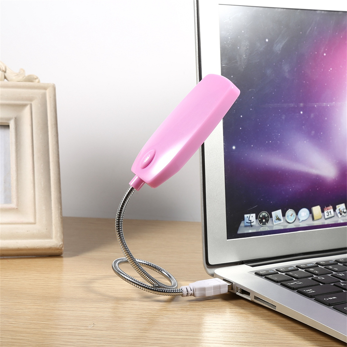 Eine pinkfarbene USB-LED-Leuchte, die an einen Laptop angeschlossen ist. Das Licht ist flexibel. Ein Bilderrahmen im Hintergrund.