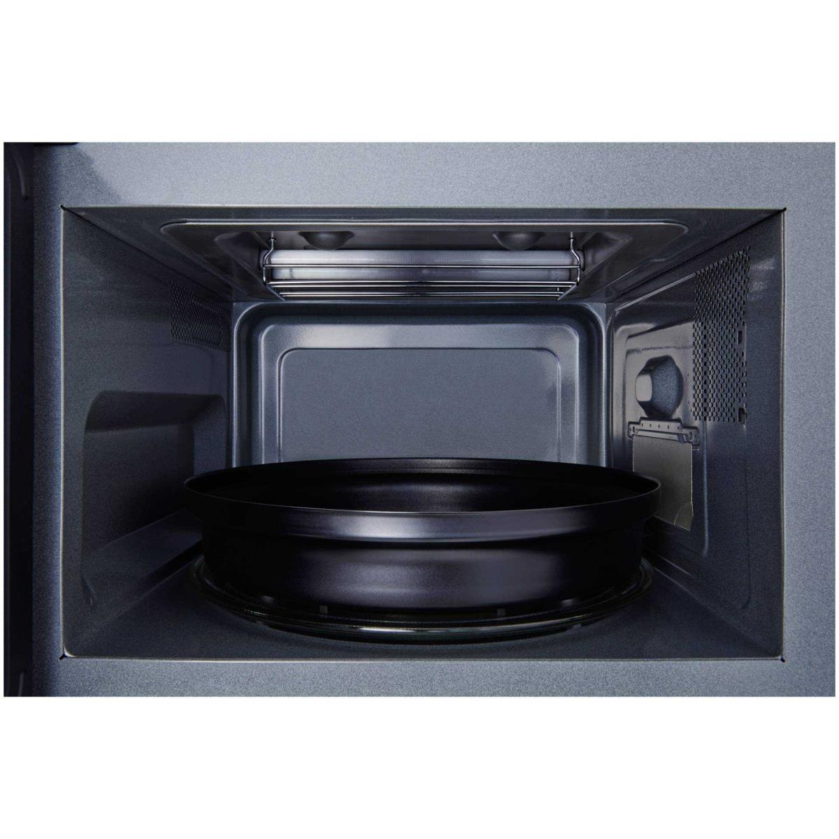 Wnętrze kuchenki mikrofalowej z czarną tacą do gotowania. Ciemne tło. Metalowy ruszt w środku.