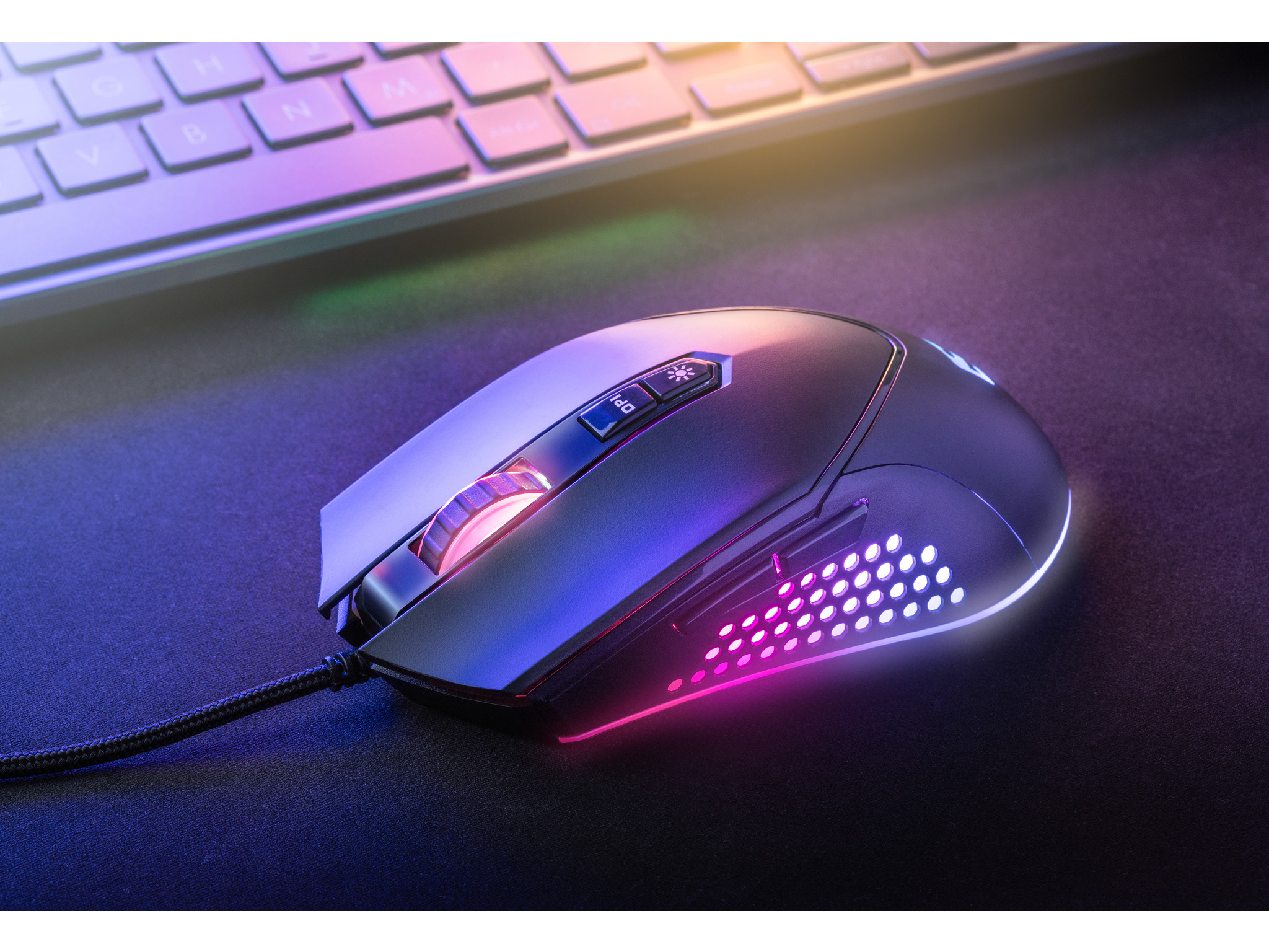 Zwarte gamingmuis, verlicht met roze en paarse lichten, ligt op een zwart muismat.