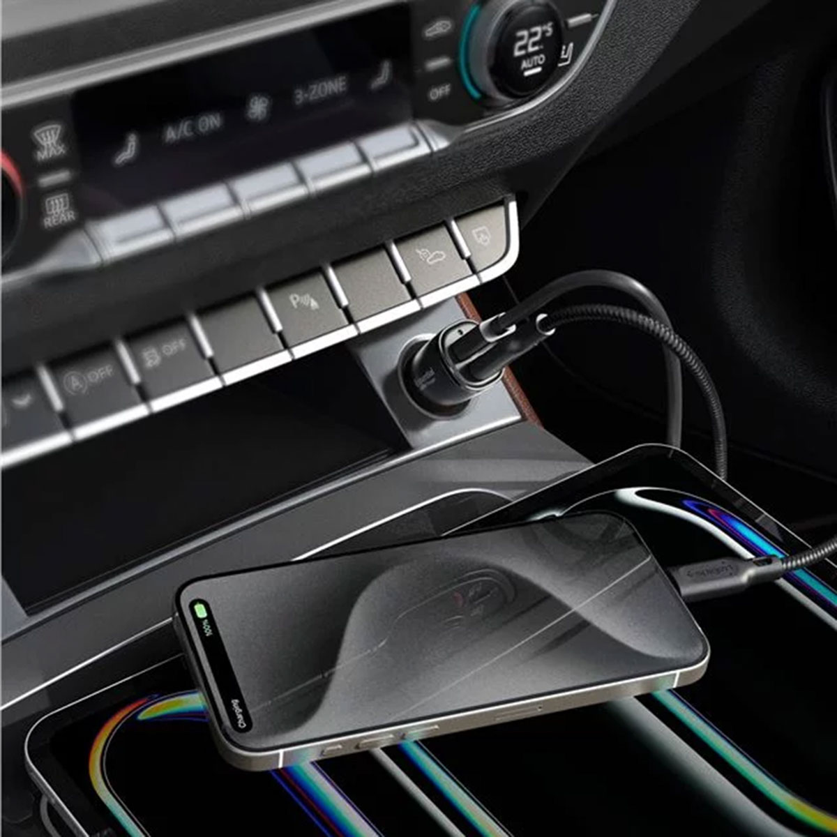 Car console with phone and charging cable. Phone displays a charging notification. Black and silver colors.