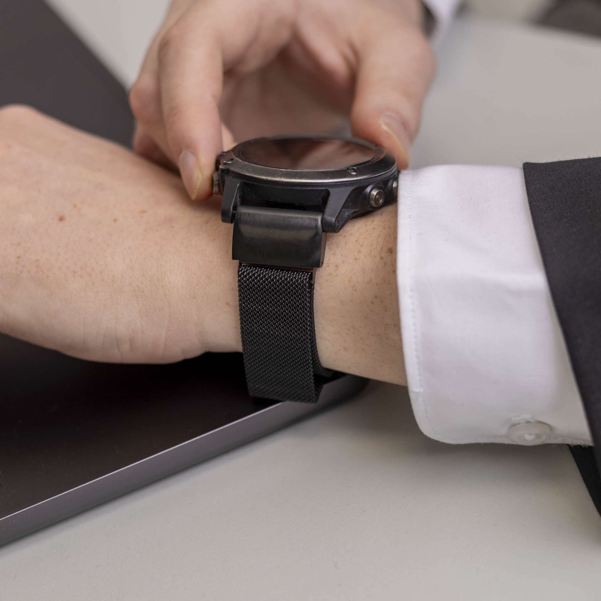 Die Hand einer Person, die eine schwarze Uhr mit schwarzem Armband am Handgelenk trägt.