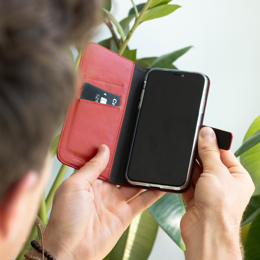 Een persoon die een telefoon in een rode hoes vasthoudt, met een creditcard zichtbaar.