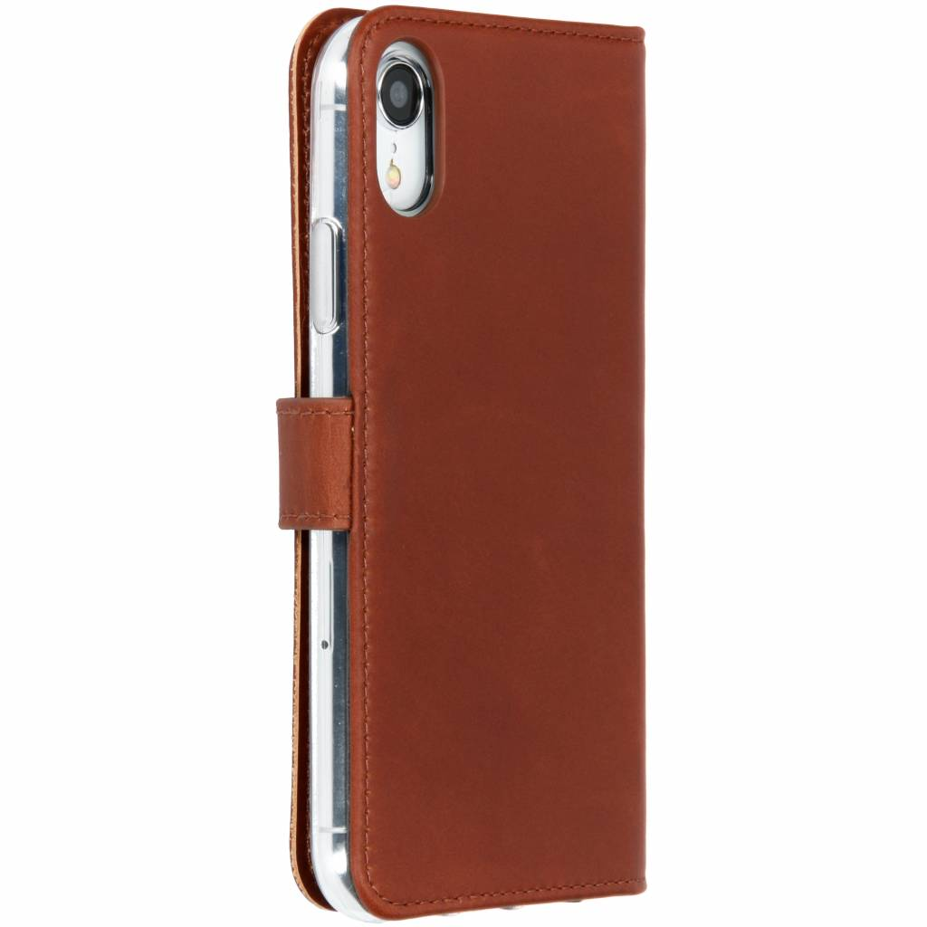 Bruine leren telefoonhoes met een telefoon erin. Het is gesloten en op een wit oppervlak.