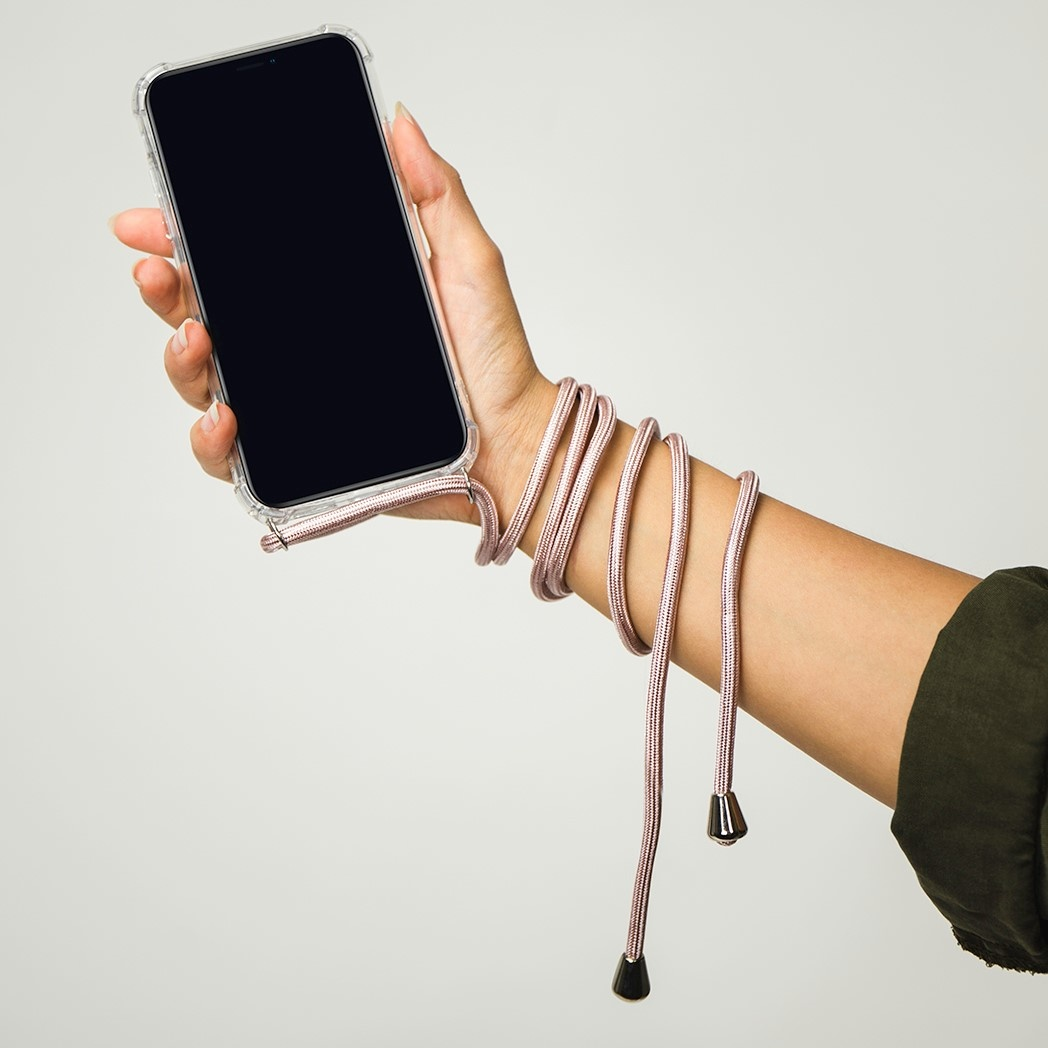 Een hand houdt een telefoon vast in een doorzichtige hoes met een roze koord. Het koord wikkelt zich om de pols.
