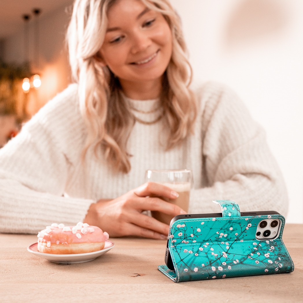 Femme avec étui de téléphone sur table avec donut et café. Motif floral sur l'étui.