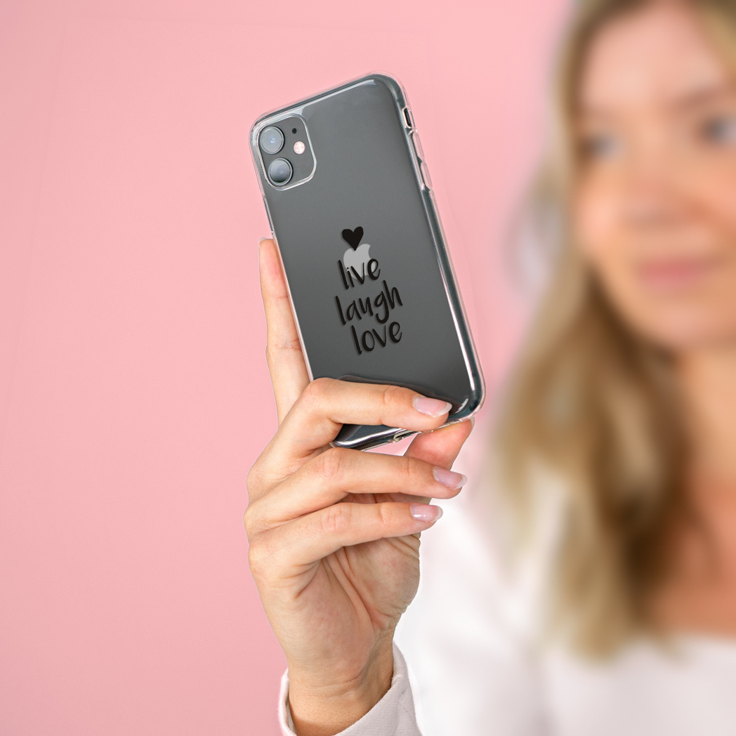 Een vrouw houdt een telefoon vast in een doorzichtige hoes met de woorden 'live laugh love' erop.