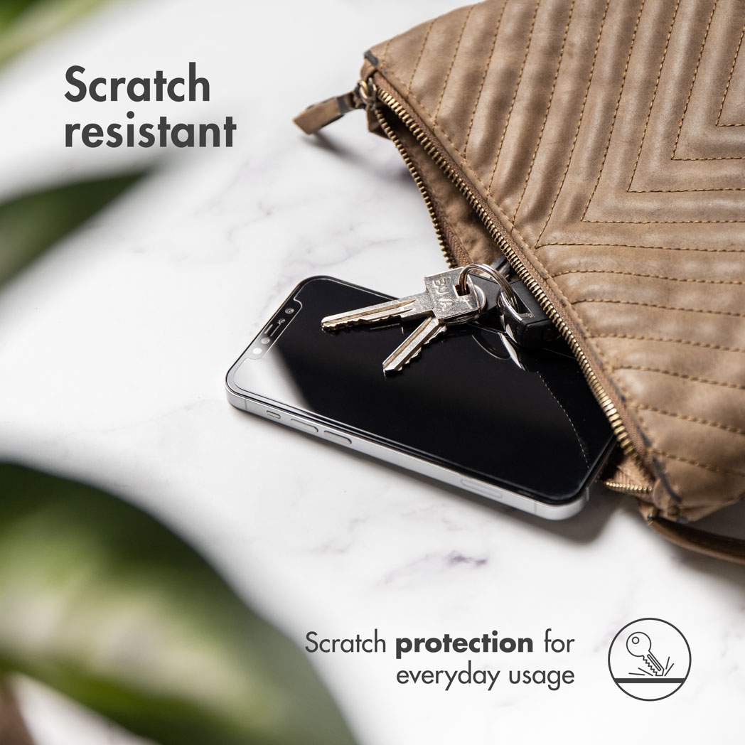 Een telefoon in een tas met sleutels ernaast. De scène bevindt zich op een marmerachtig oppervlak.