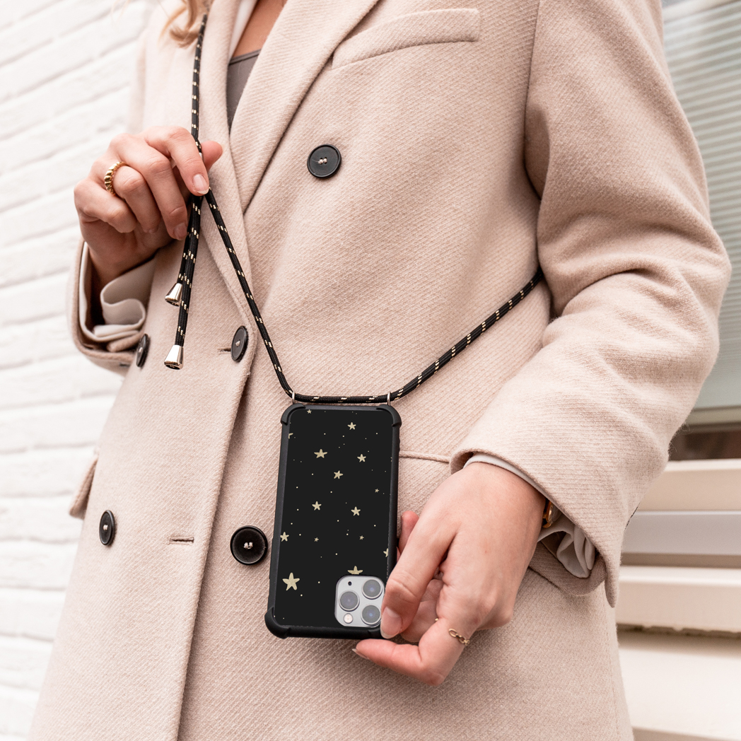Een vrouw met een jas met een telefoonhoesje met sterren die aan een riem hangt.