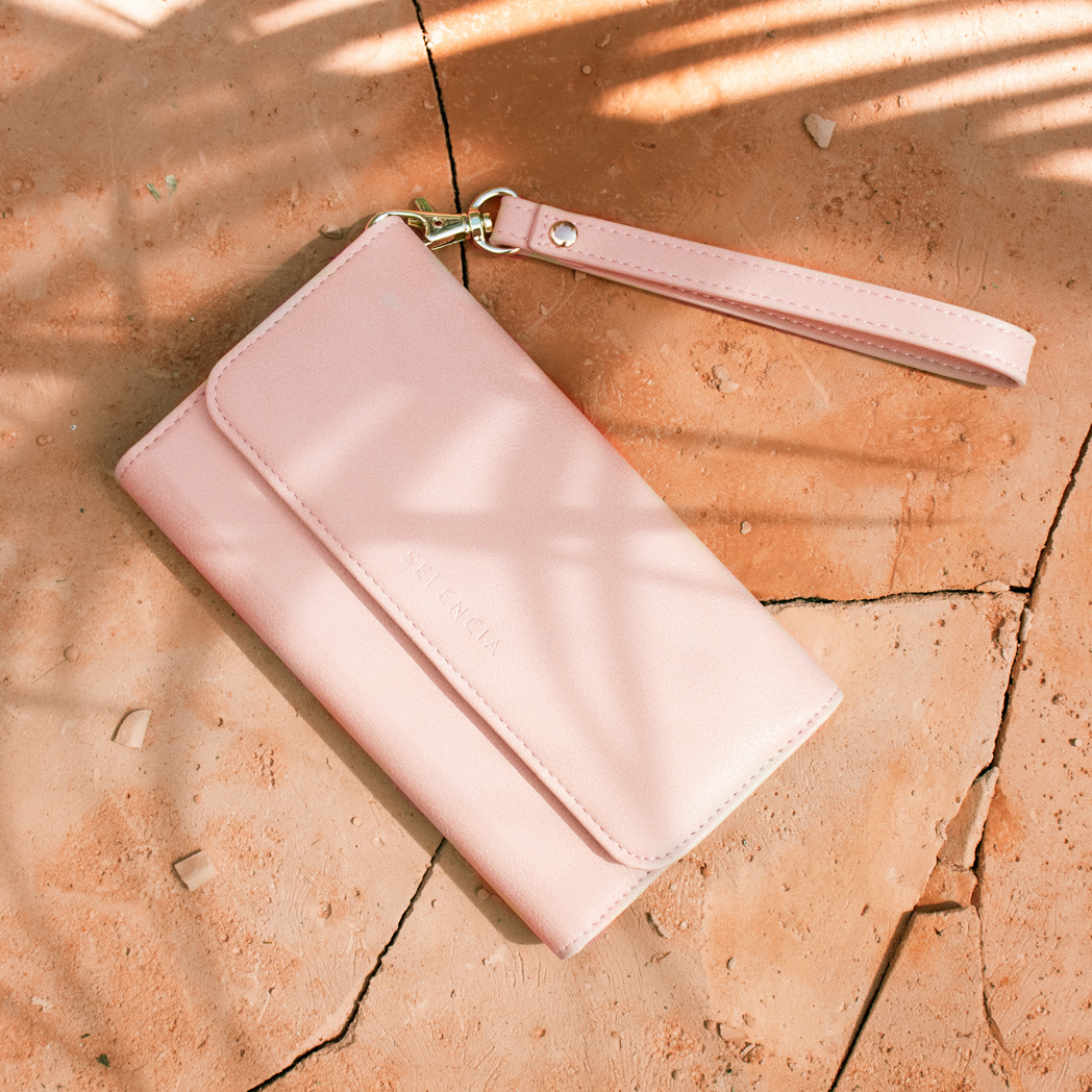 Un portefeuille rose avec une sangle sur une surface texturée. Le mot SILENCIA est visible.