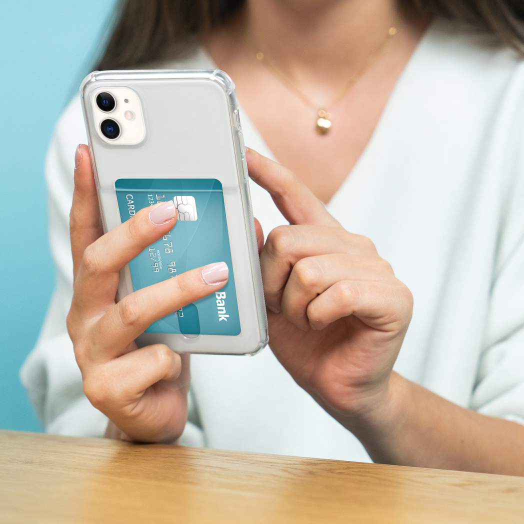 Una donna tiene in mano un telefono con una carta nella custodia. Lo sfondo è un muro blu.
