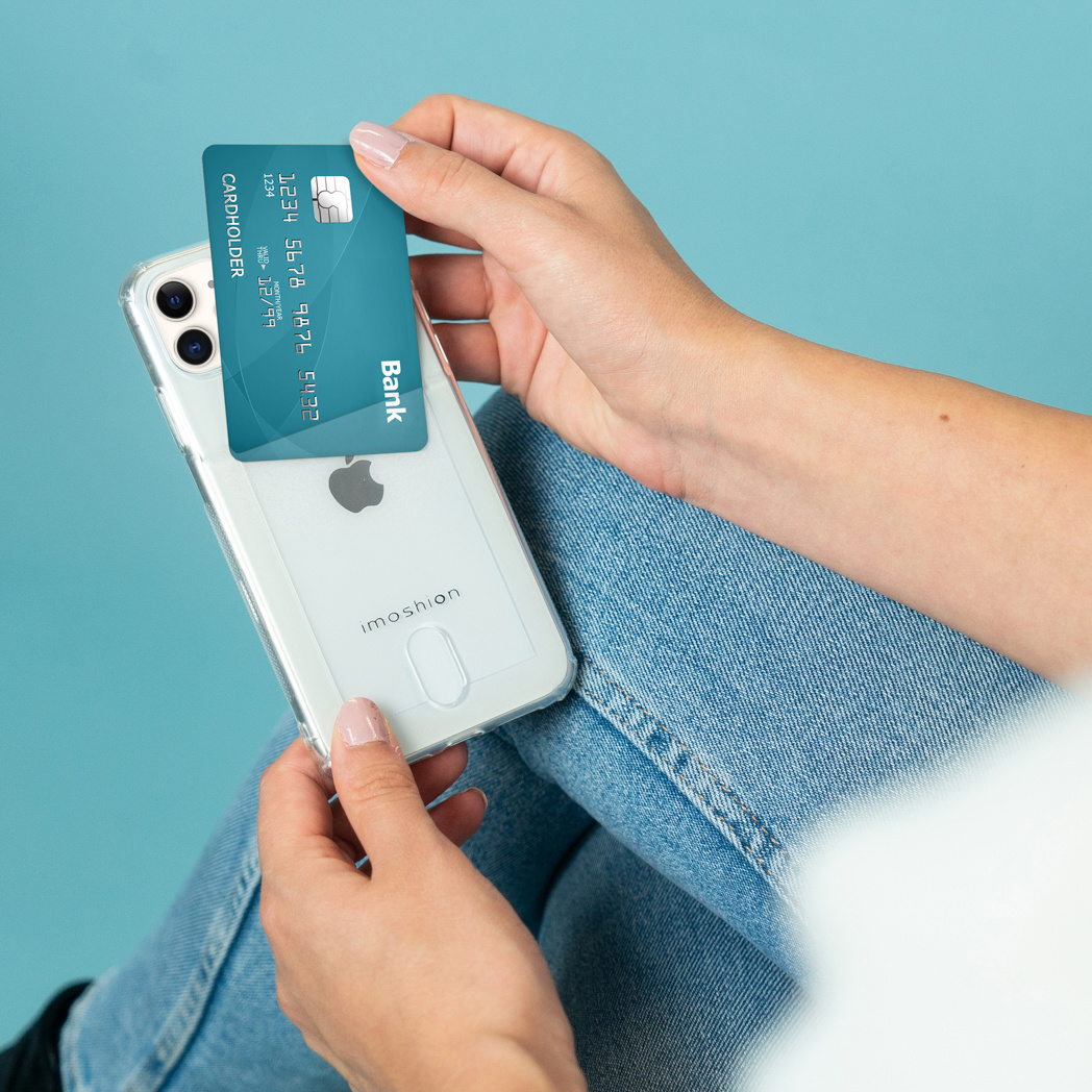 Mani che tengono una custodia trasparente per telefono con una carta di credito all'interno, su sfondo blu.