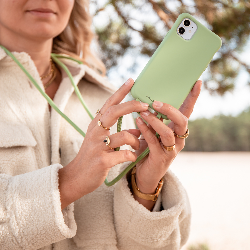 Vrouw die een groene telefoon in handen houdt, met ringen en een groene band.