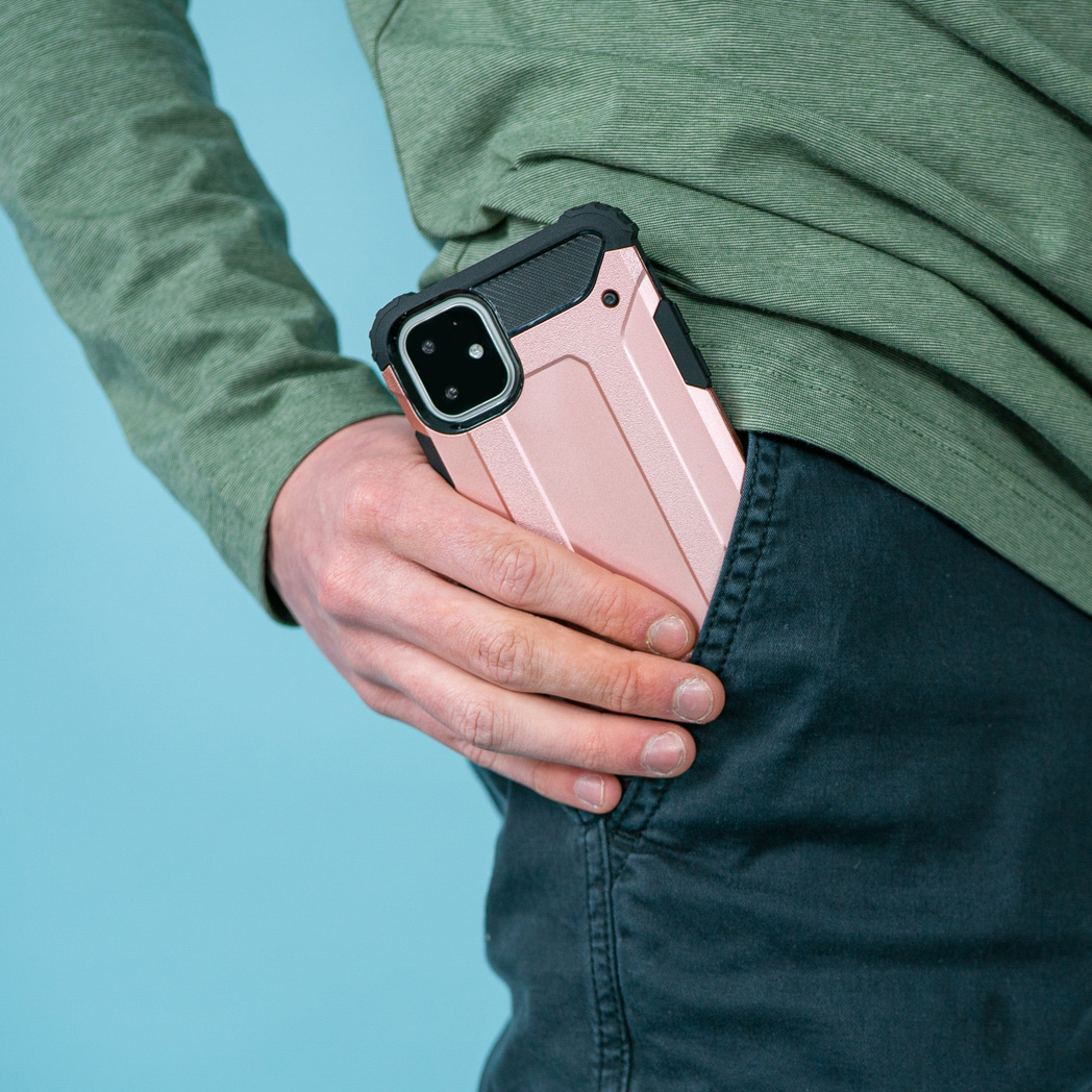 Een telefoon in een roze hoesje, deels zichtbaar in een zak, op een blauwe achtergrond.