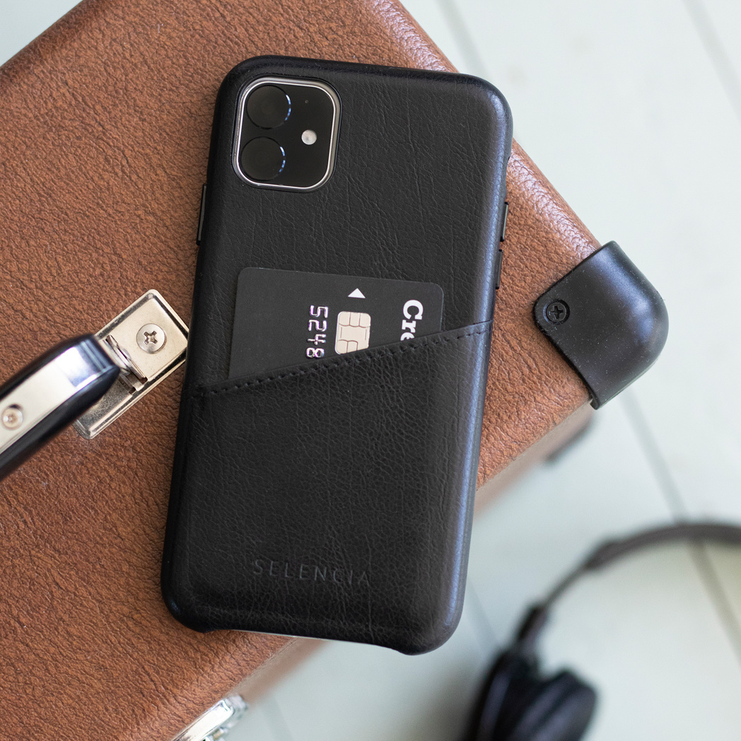 Un étui de téléphone noir avec une carte de crédit dans la poche, posé sur une valise.