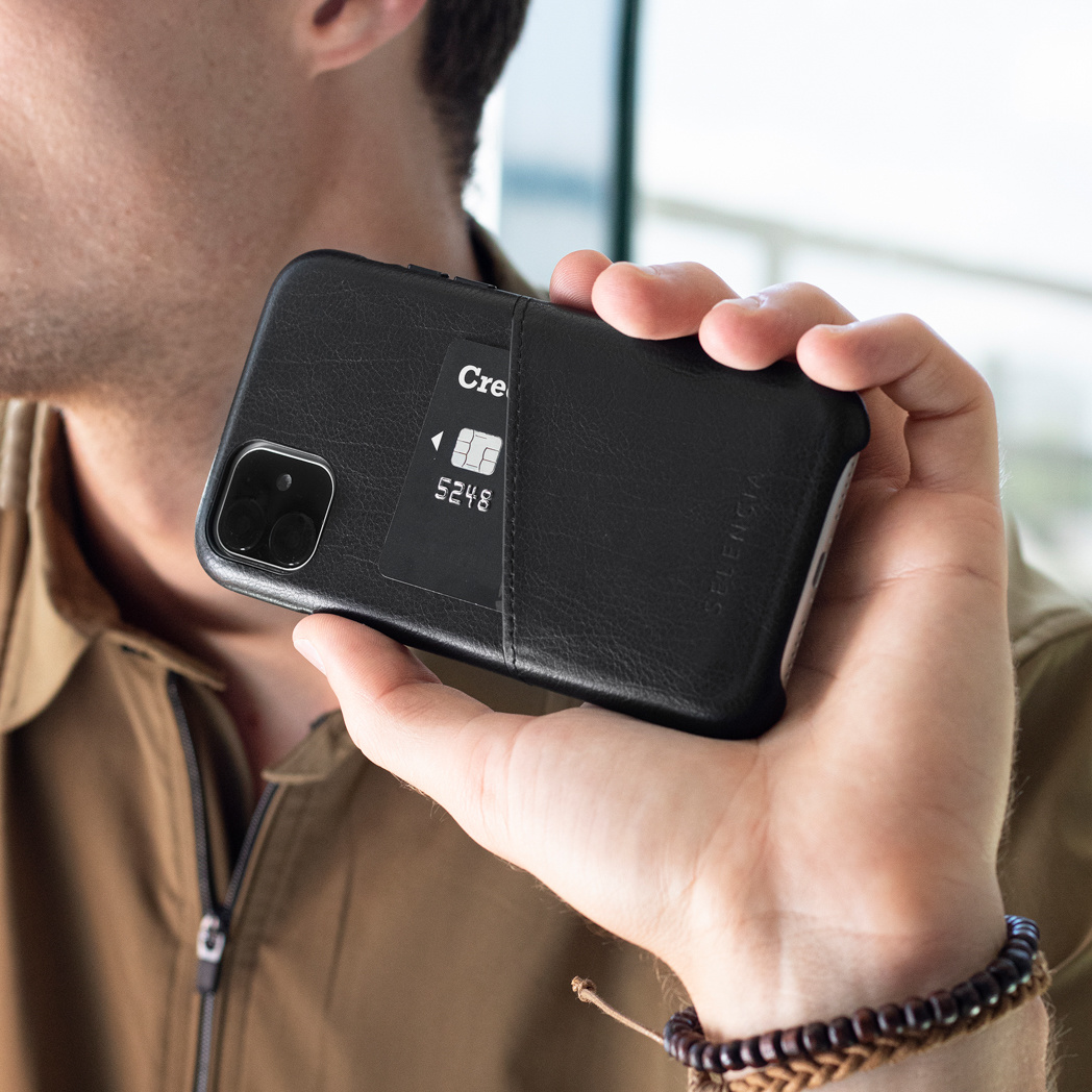 Une personne tient un étui de téléphone noir avec une carte de crédit. L'étui est en cuir.