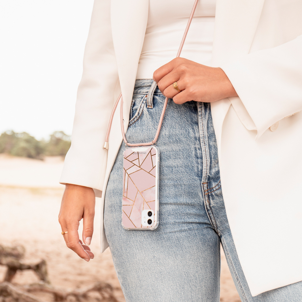 Vrouw met roze telefoonhoesje met bandje. Jeans en witte jas zichtbaar.