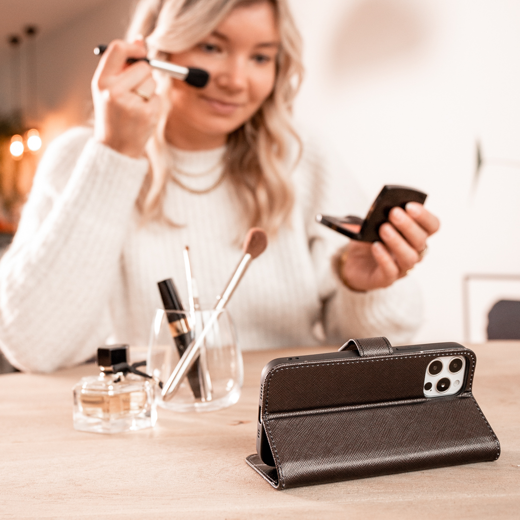 Femme qui se maquille pendant qu'un téléphone dans un étui est sur la table.
