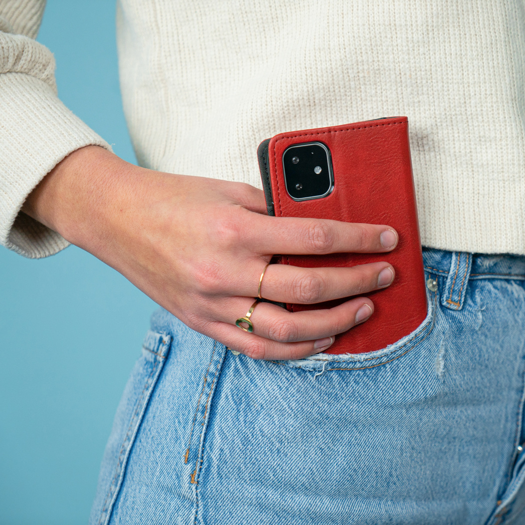 Hand in een jeanszak met een rode telefoonhoes.