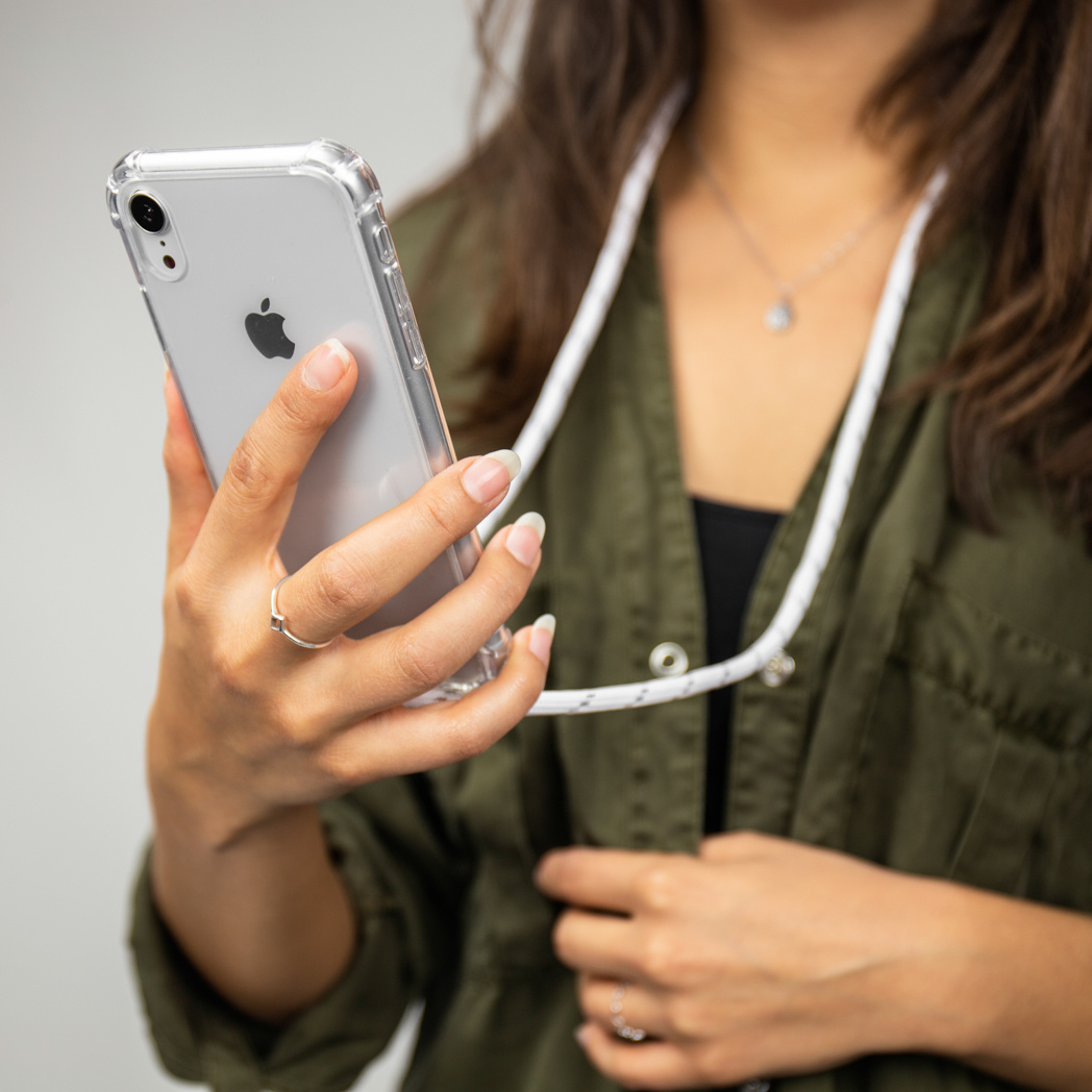 Een vrouw die een telefoon vasthoudt met een doorzichtige hoes en een koord.