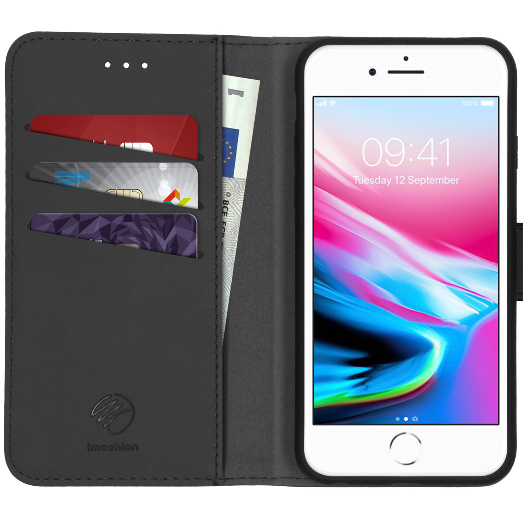 Geopende zwarte telefoonhoes met creditcards, contant geld en een witte iPhone met de tijd en datum.