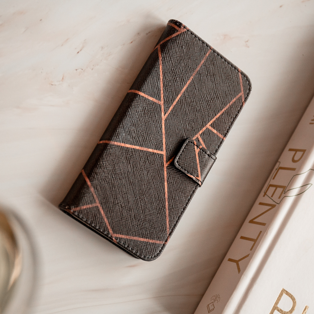 Telefoonhoesje met een oranje geometrisch patroon. Een boek is op de achtergrond geplaatst.