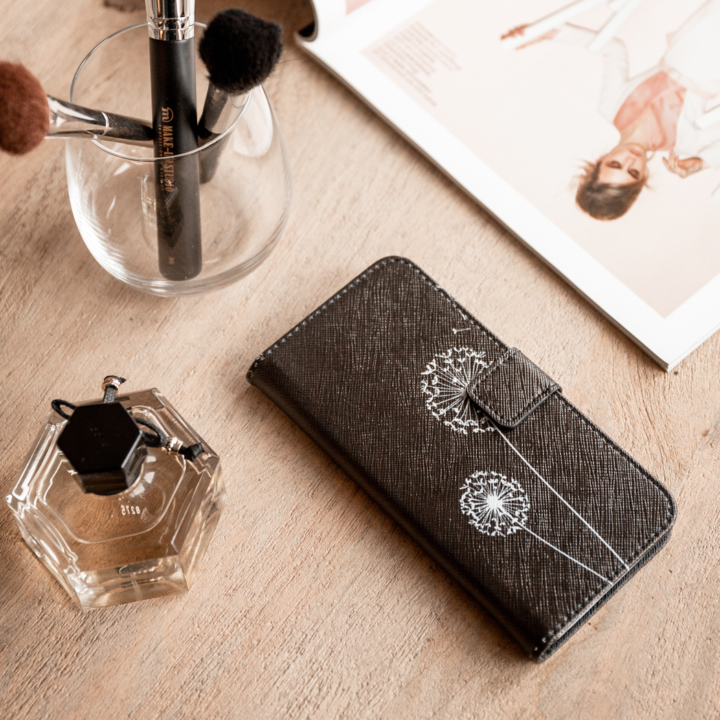 Coque de téléphone avec des pissenlits sur une surface en bois, avec des pinceaux de maquillage et du parfum.