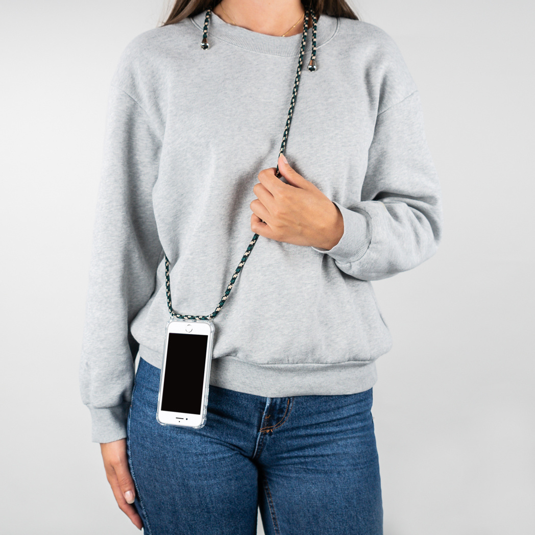 Une femme portant un sweat-shirt gris et un jean, tenant un téléphone avec un cordon.