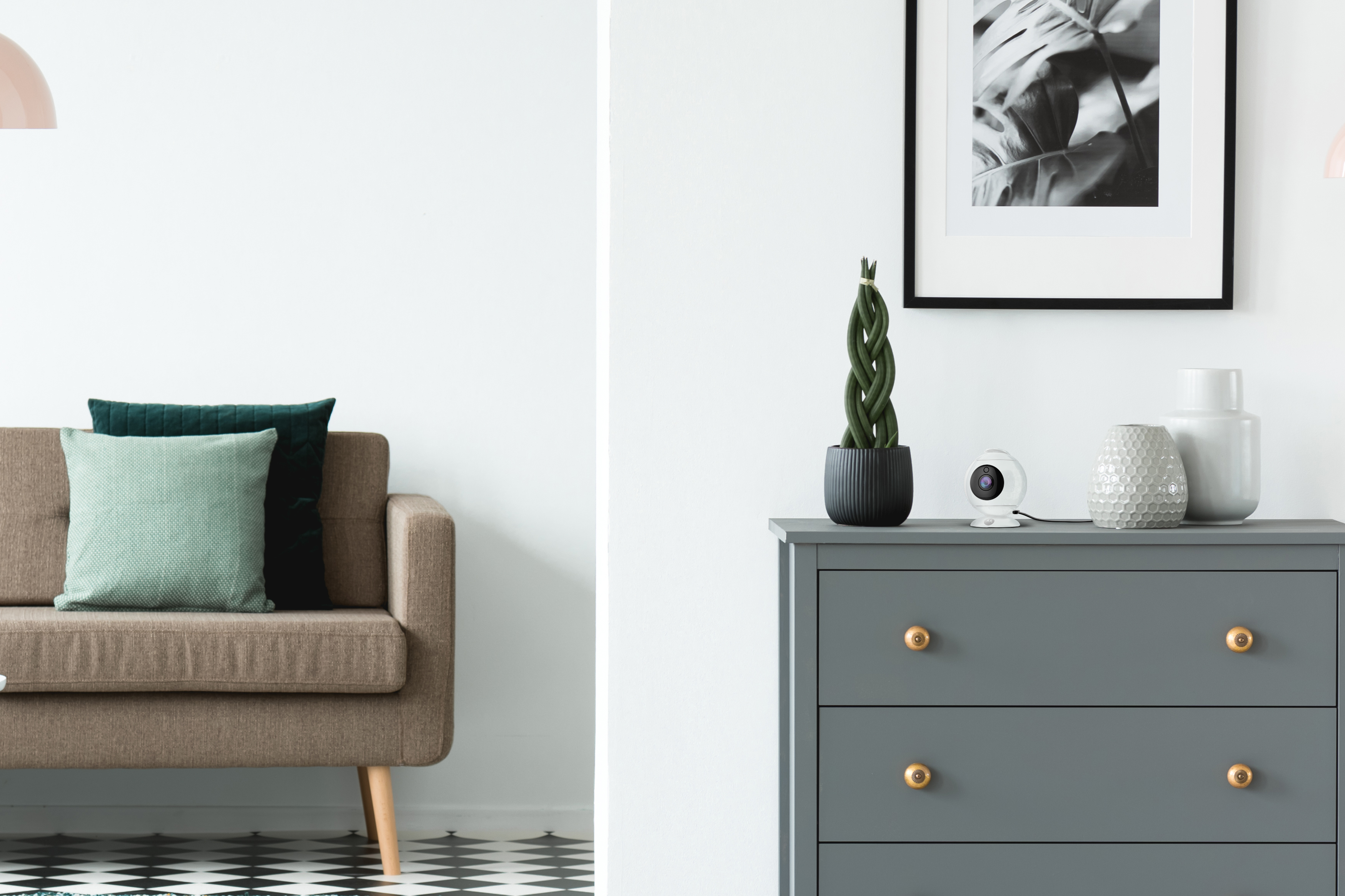 A living room with a sofa, pillows, and a chest of drawers. A picture on the wall.