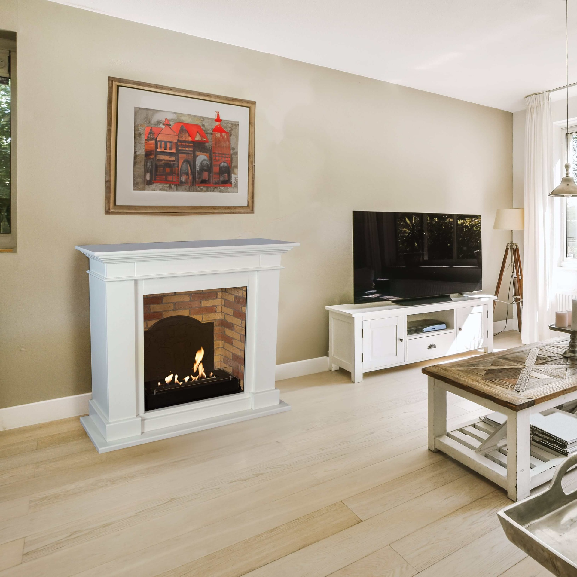 Een woonkamer met een witte open haard, tv en een schilderij van gebouwen. Lichte houten vloeren en beige muren maken het af.