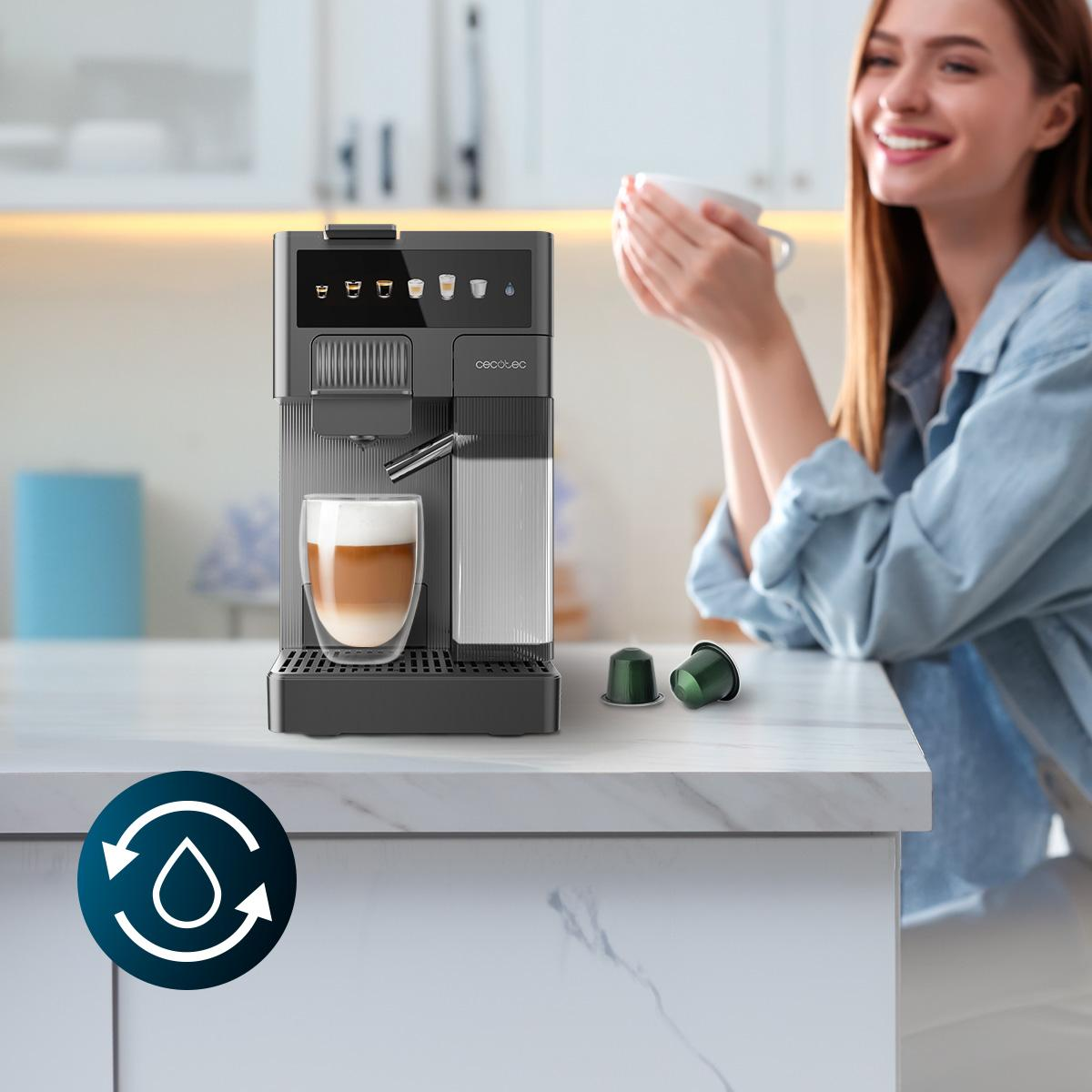 Máquina de espresso con un vaso de latte. Mujer sonríe en el fondo, sosteniendo una taza.