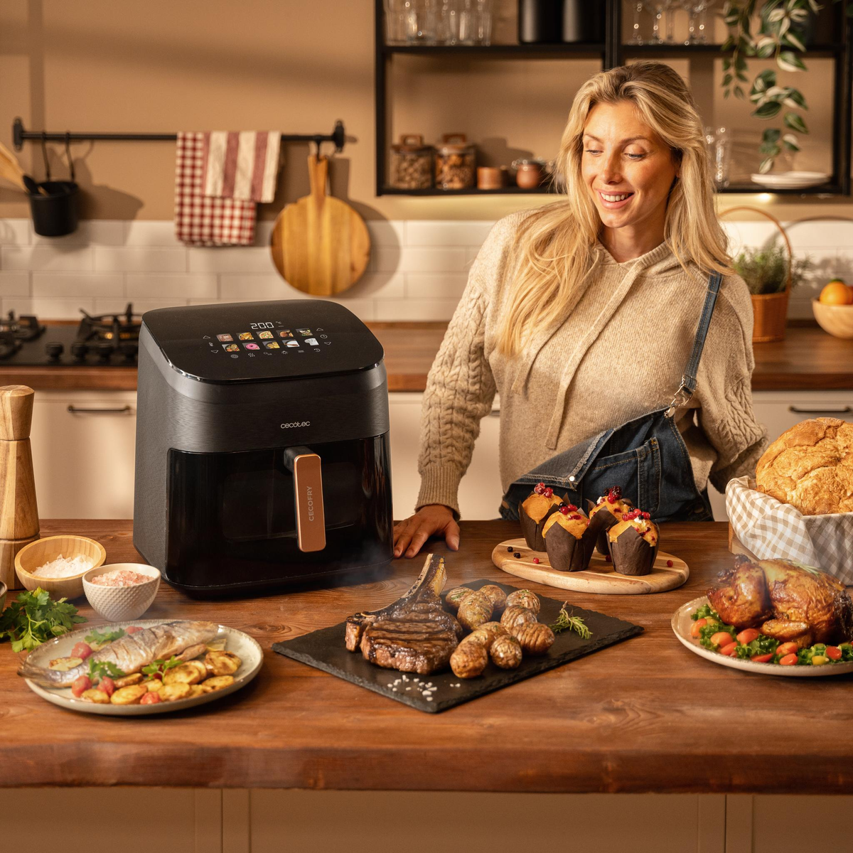 Donna e cibo su un tavolo di legno. Friggitrice ad aria, bistecca, patate arrosto e muffin.