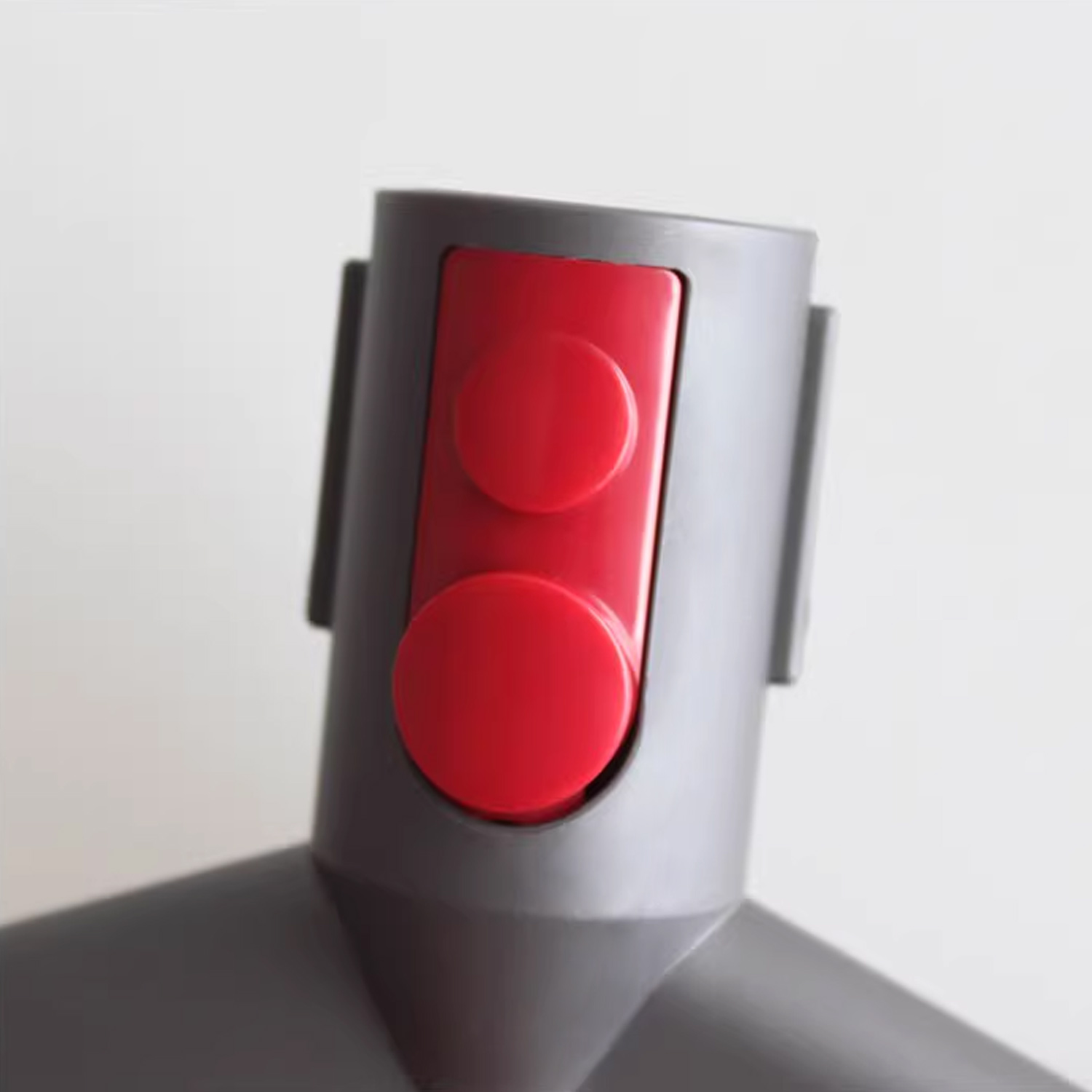 Zbliżenie szarej głowicy odkurzacza z dwoma czerwonymi przyciskami.